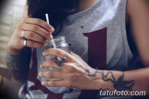 Фото тату на руке с детально проработанным рисунком и стаканом с напитком, демонстрирующее современный стиль и индивидуальность.